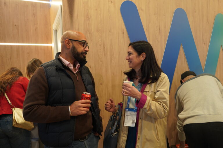 Two people talking at a fair with drinks in their hands