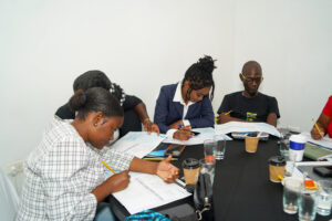 A group of people sitting on a table filling out sheets