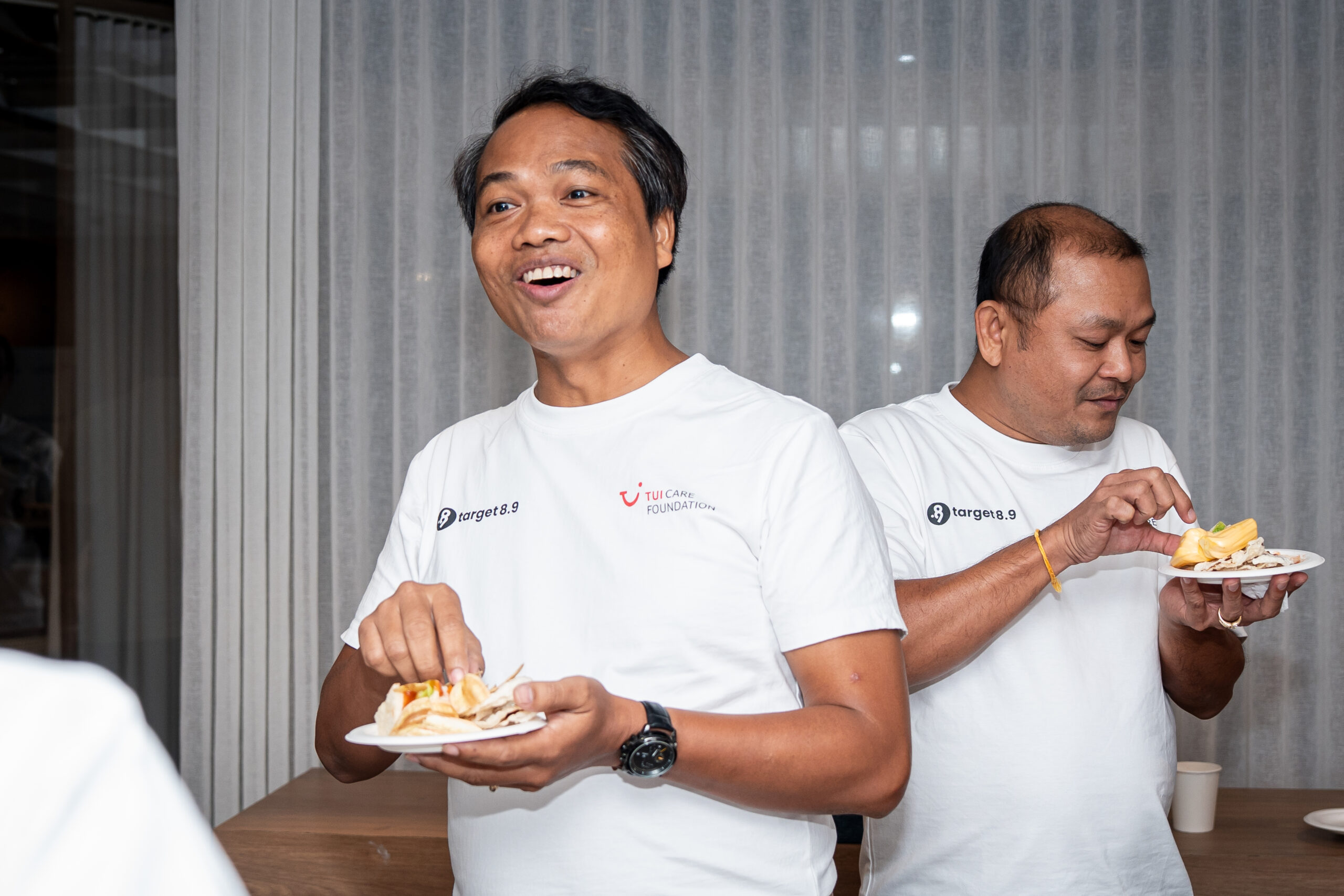 Two men eating, chatting, and smiling