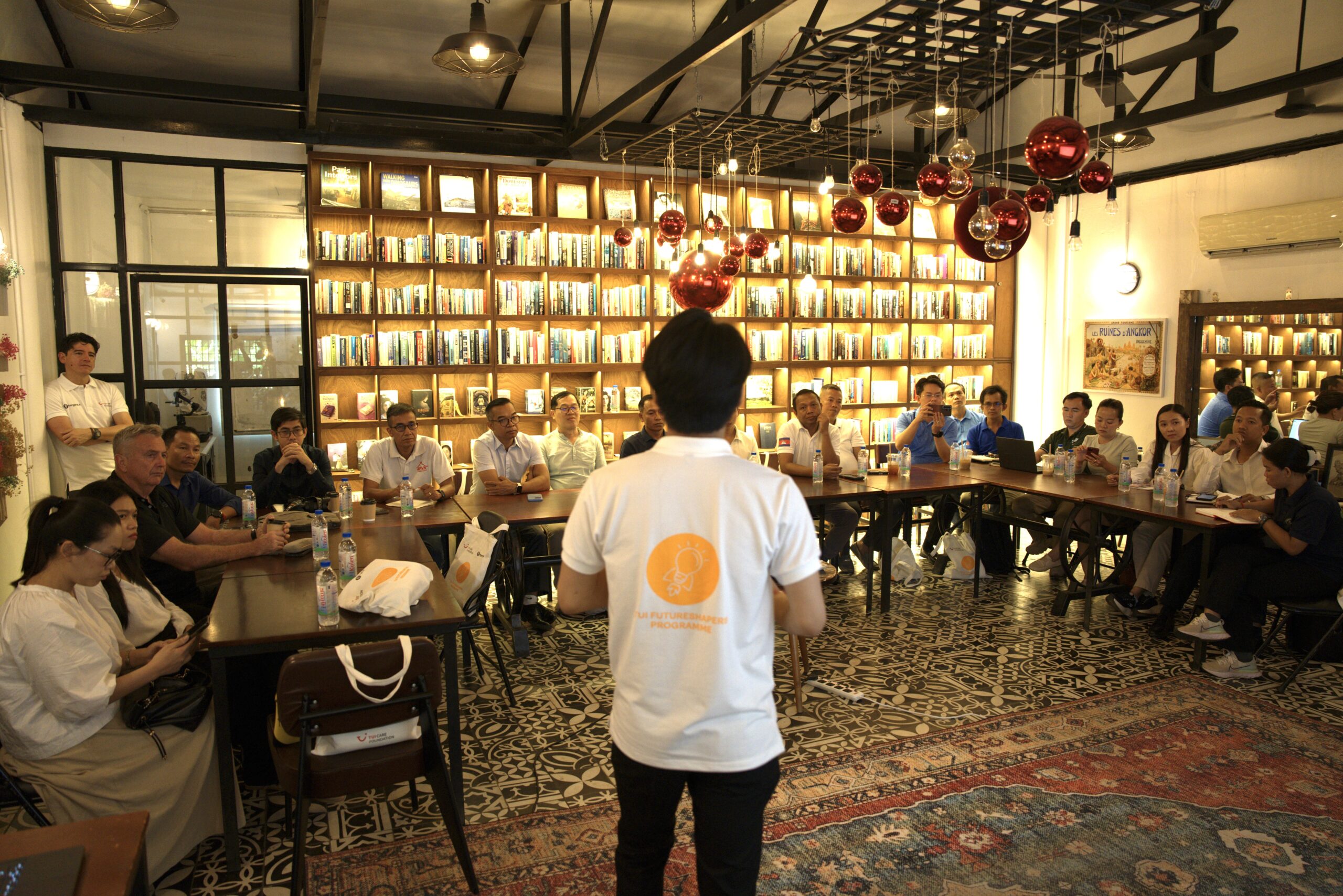 Someone standing in the middle presenting with a group of people sitting at a U-shaped table listening