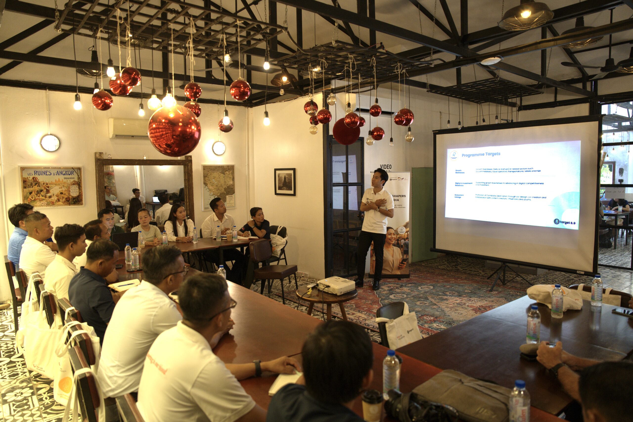 A group sitting a a U-shaped table and looking at a presentation