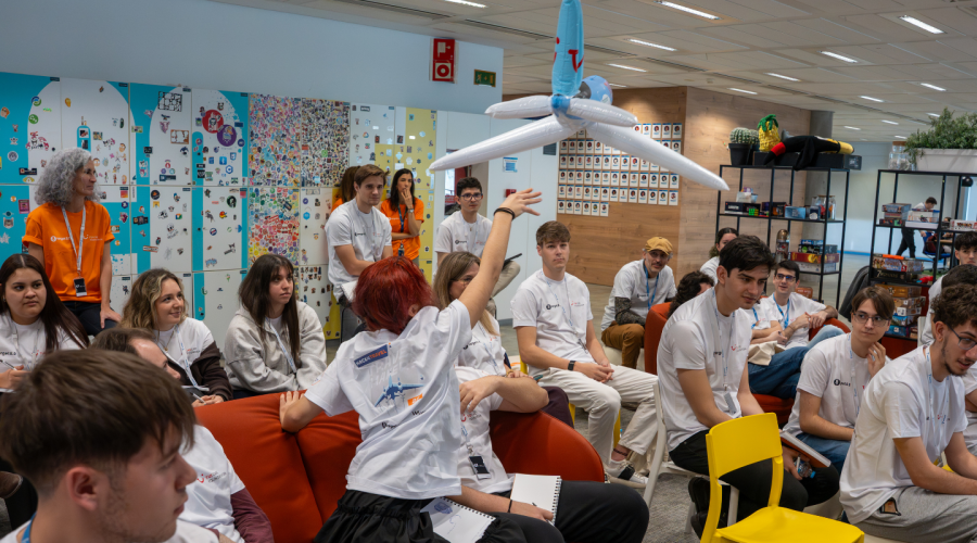 a group of people looking sitting in the audience passing a inflatable airplane