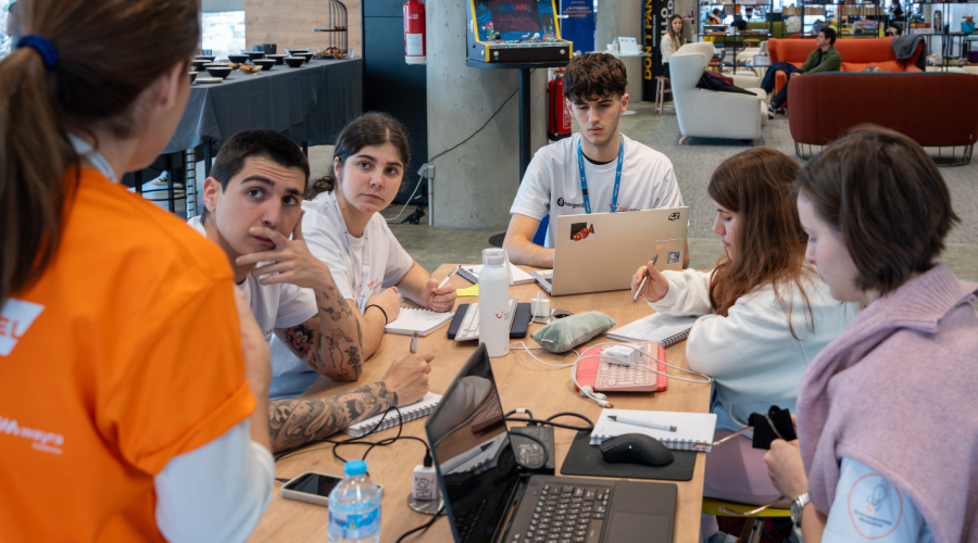 people sitting in front of computers and one person is standing explaining them something