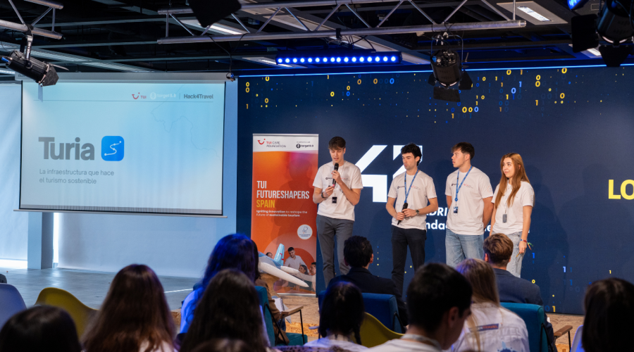 four people standing on stage holding a presentation