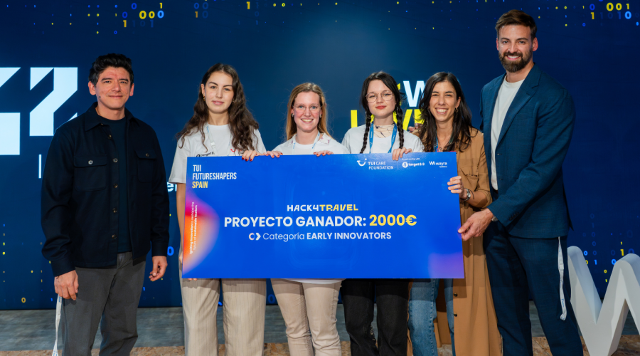 four women and two men standing behind the winning team's check
