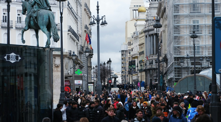 a crowd of people walking down a street next to tall buildings